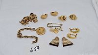 Full lot displaying all jewelry pieces arranged on a white background including bracelet, multiple pairs of clip earrings and pin.