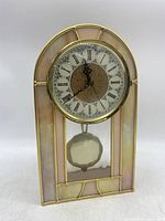 Front view of stained glass mantle clock with Roman numeral clock face and pendulum visible below.