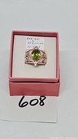 Front view of sterling silver and peridot ring in pink box with handwritten tag "PERIDOT STERLING 11.5 SR"