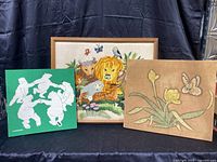 Three vintage/retro fabric and crewel art pieces shown together on black cloth background with black curtain background.