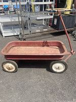 Side view of vintage red metal wagon showing overall condition and handle