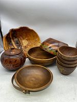 Display of various wooden bowls and a lidded wooden container, showing natural and painted finishes