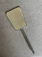 Front view of the antique hand mirror showing the rectangular glass mirror and silver-colored metal handle.