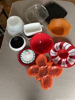 Assorted plastic containers, bowls and serving dishes on table in natural light.