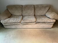 Front view of beige three-seater sofa illustrating fabric wear and seat cushions