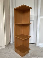 Front angled view of the IKEA light brown wooden corner shelving unit showing three shelves and overall structure.