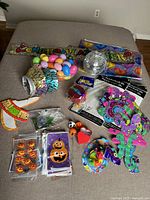 Overall view of assorted party supplies displayed, including a Congratulations banner, plastic Easter eggs, Halloween pumpkin decorations, disco ball, and party hats.