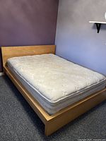 Photo of queen size IKEA Malm bed frame with light wood finish showing the full bed with mattress in a room with blue and purple walls.