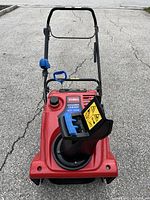 Front view showing red steel housing, plastic chute, serrated auger and Toro logo on top deck