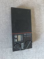 Front view of vintage Maclean's AM/FM transistor radio showing speaker grill, quartz display, volume and tuning dials, and switches.
