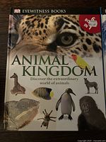 Front cover of Animal Kingdom DK Eyewitness book featuring images of animals including a jaguar, giraffe, penguin, spider, and gorilla with text.