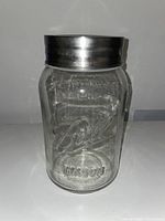 Front view of clear Ball glass Mason jar with metal screw-on lid showing embossed Ball logo and Mason lettering on the jar body.