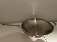 View of the frying pan's interior and long handle, showing signs of use and minor stains on the cooking surface.
