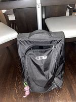 Front view of the large black fabric Grit hockey and figure skating bag with visible handle and zippered pocket with logo.