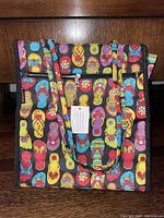 Front view of Johnson fabric tote bag with colorful flip-flop pattern on black background, with attached original tags visible.