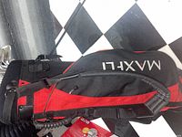 Red and black Maxfli branded golf bag with padded shoulder strap and zipper compartments shown upright.