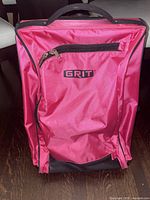 Front view of the pink Grit skating bag with zippered front pocket and logo