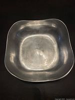 Top-down view of the silver wavy square bowl showing interior surface, wear and reflections.