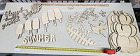 Top overview showing all wooden cutout pieces spread out on table including words, ice cream shapes, pumpkin, and seasonal designs.