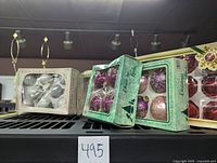 Photo showing multiple boxed sets of Christmas baubles in white, purple, and red colors with transparent packaging.