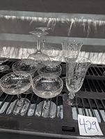 View of 10 etched crystal goblets grouped together, showing variety of tall footed juice tumblers and wider goblets with floral etching.