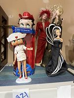 Five dolls on display including Betty Boop Nurse doll, boxed Betty Boop doll, Marilyn doll in gold dress, and others.