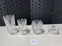Four Bohemia crystal vases of varying sizes and designs placed side by side on a white surface with dark background.