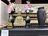 Photo showing all items including two hand painted vases, two flying horse plastic vases with artificial flowers, black glass vase with character, meditation Buddha statue, and small brass Buddha with crack