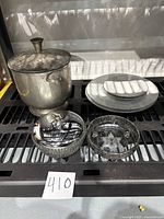 Lot overview showing metal ice bucket with lid, stack of fine china plates including two dinner and two bread plates, and two candy dishes (one metal with lid, one footed clear glass).