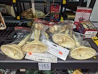 Multiple beige 1-light candoliers in plastic packaging, boxes of multi-color Christmas light sets, and a brass candolier with a pink candle on a table.