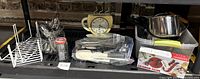 Photo showing assorted kitchen utensils, a coffee clock, bottle opener set, and kitchen shelf racks.