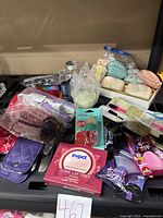 Lot of assorted nautical decorative soaps, makeup brushes, lip products, nail items, bandanas, brushes, and a pump lid arranged on a shelf