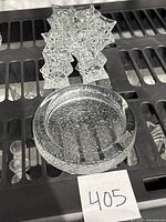 One Finnish glass ashtray, round with a textured pattern and rim, placed on a shelf.