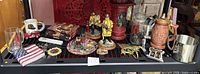 Firefighter-themed beer steins, mugs, figurines, magnets, wall hook, and Rescue Me DVDs displayed on a black shelf