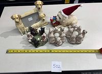 Overview showing 3x5 photo frame with three yellow Labradors, Christmas Labrador figurine with Santa hat holding ornaments, black and cream Labradors figurines in a circle, and two candle holders featuring Labrador figurines arranged around the candles.