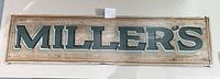 Front view of the full wooden sign with 'MILLER'S' painted in bold letters