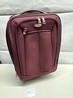 Front view of burgundy Samsonite carry-on suitcase showing front zippered compartment and padded handle.