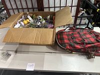 Photo showing box with assortment of solar dancing sun toys and a small plaid backpack on table