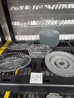 Photo showing multiple cut glass items: shallow bowls, salad plates stacked, floral etched relish dish, and divided relish trays.