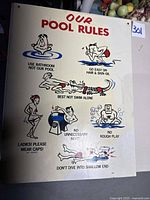 Full view of the vintage metal pool rules sign with visible discoloration and some dirt marks