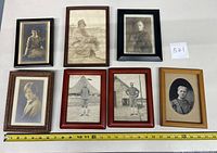 Seven vintage framed black and white portrait photographs arrayed on a white surface, featuring mixed styles of wooden frames.