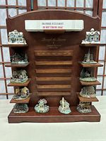 Front view of wooden calendar stand with 12 small collectible village houses on shelves.