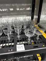 Shelf display of 14 clear etched vintage glasses including 6 wine glasses, 3 coupes, and 5 cordial glasses with varied etched designs.