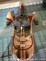 Top view angled photo of the 1995 Kenner Power of the Force Luke Skywalker X-34 Landspeeder toy showing the cockpit canopy and the two thrusters separated by a central nose section. The toy is sand-beige with brown striping and has some dust and dirt.
