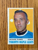 Front showing Jacques Plante portrait in Maple Leafs uniform on yellow background.