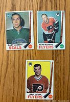 Front view of three hockey cards showing players Gary Jarrett (Seals), Ralph MacSweyn (Flyers), Andre Lacroix (Flyers) in team uniforms with O-Pee-Chee logo and player names.