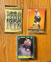 Front view of three sealed hockey card packs/sets including 1992 O-Pee-Chee Premier, Patrick Lalime Upper Deck, and Eric Lindros set.