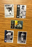 Top view of five Joe DiMaggio baseball cards on wooden surface showing front sides with different designs including photos and holographic elements