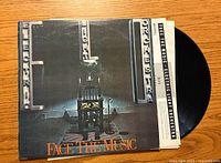 Front cover of the Electric Light Orchestra 'Face the Music' vinyl album showing the chair with lightbulbs and title.