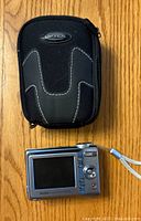 Kodak EasyShare C713 digital camera back showing LCD screen and control buttons alongside Optex black zippered carrying case